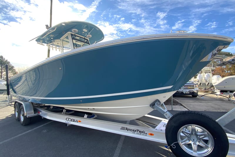 2026 Cobia 285 Center Console boat on trailer, blue hull, sunny day.
