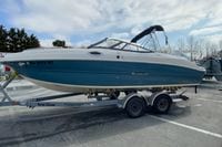 2023 Stingray 231 DC boat on trailer, parked outdoors under cloudy sky.