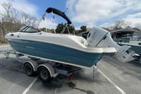 2023 Stingray 231 DC boat on trailer with Suzuki outboard motor in parking lot.