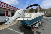 2023 Stingray 231 DC boat with Suzuki outboard motor on trailer at dealership.