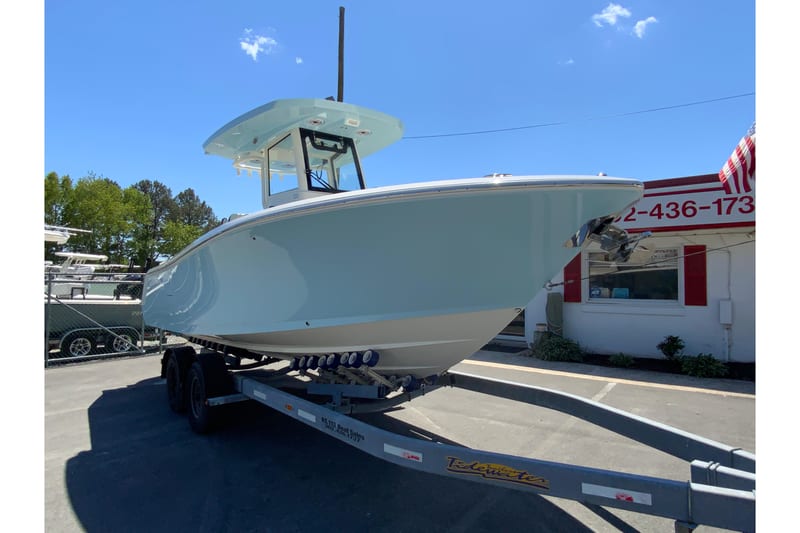 2026 Cobia 245 Center Console boat on trailer, parked outdoors under clear blue sky.