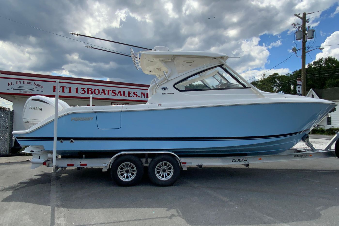 2026 Pursuit DC 286 Dual Console boat on trailer at dealership, cloudy sky background.