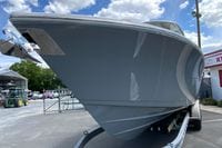 2027 Cobia 320 Center Console boat on trailer, viewed from the front under a blue sky.