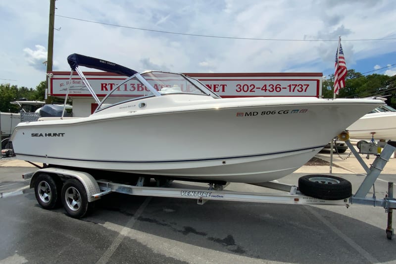 2014 Sea Hunt Escape 211 LE boat on trailer at dealership, with American flag in background.