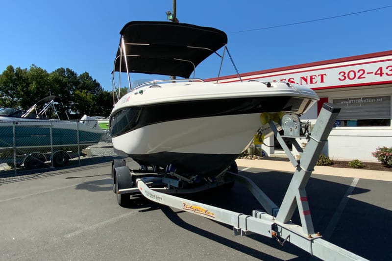2010 Hurricane SunDeck Sport 200 OB boat on trailer, parked outside dealership.