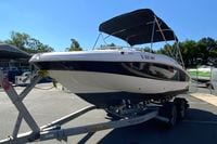 2010 Hurricane SunDeck Sport 200 OB boat on trailer, parked outdoors under clear blue sky.