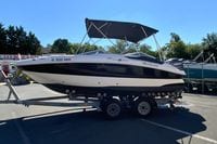 2010 Hurricane SunDeck Sport 200 OB boat on trailer, parked outdoors.