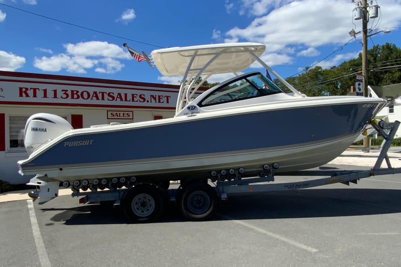2024 Pursuit DC 246 Dual Console boat on trailer at dealership, clear sky background.