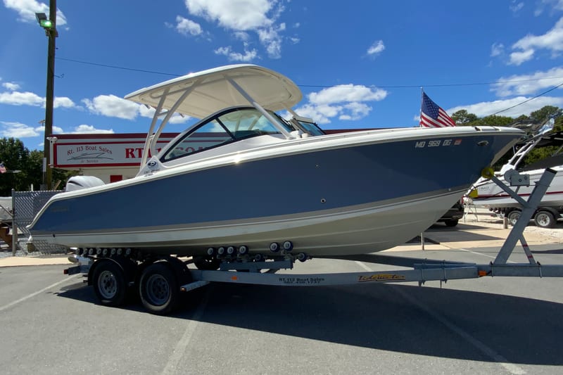 2024 Pursuit DC 246 Dual Console boat on trailer at dealership, under clear blue sky.