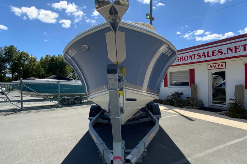 2024 Pursuit DC 246 Dual Console boat on trailer at dealership under blue sky.