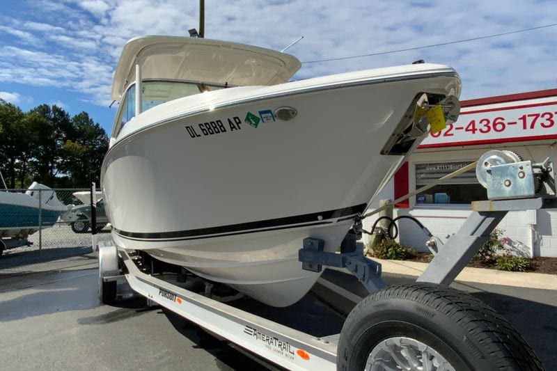 2024 Pursuit DC 266 Dual Console boat on trailer, parked outdoors under a blue sky.