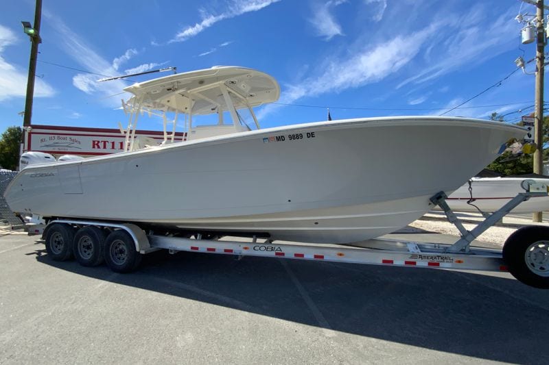 2024 Cobia 320 Center Console boat on trailer under clear blue sky.