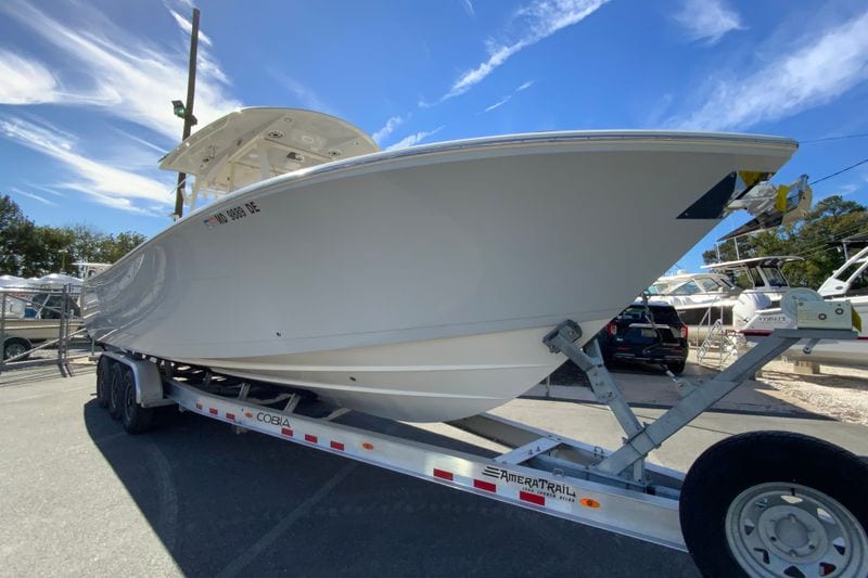 2024 Cobia 320 Center Console boat on trailer under clear blue sky.