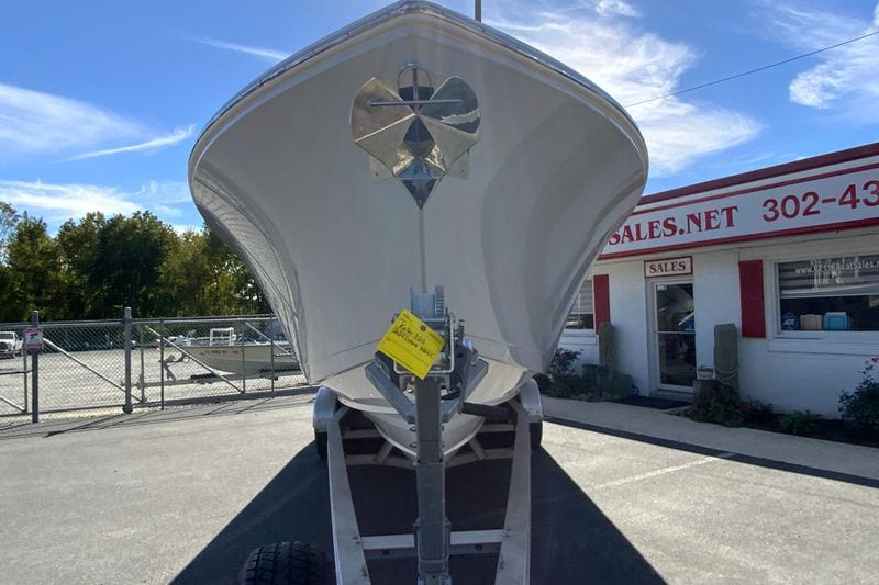 2024 Cobia 320 Center Console boat on trailer at dealership under blue sky.