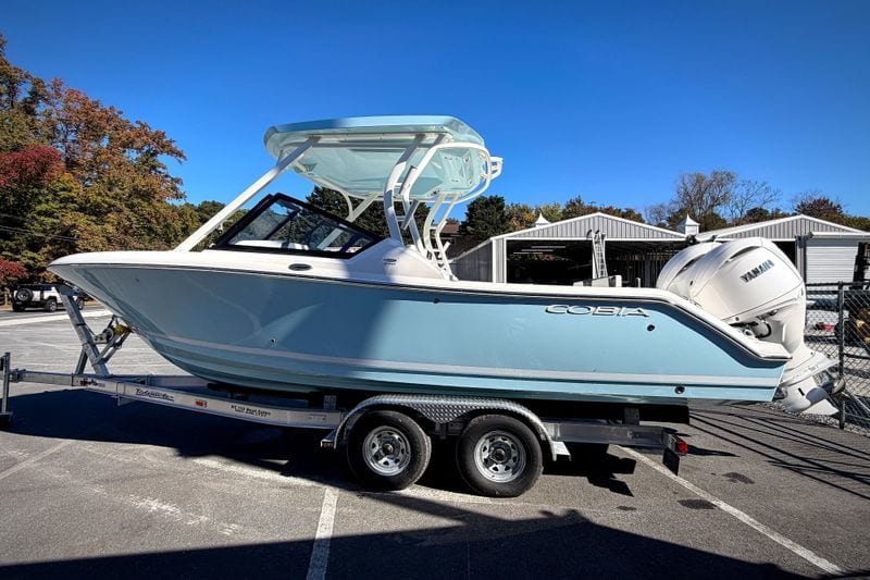 2027 Cobia 250 Dual Console boat on trailer, parked outdoors under clear blue sky.
