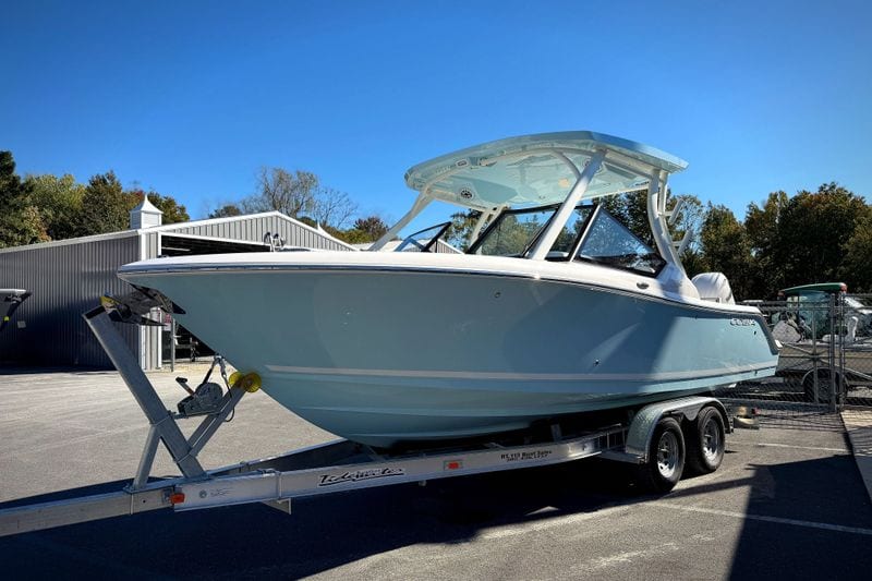 2027 Cobia 250 Dual Console boat on trailer, parked outdoors under clear blue sky.