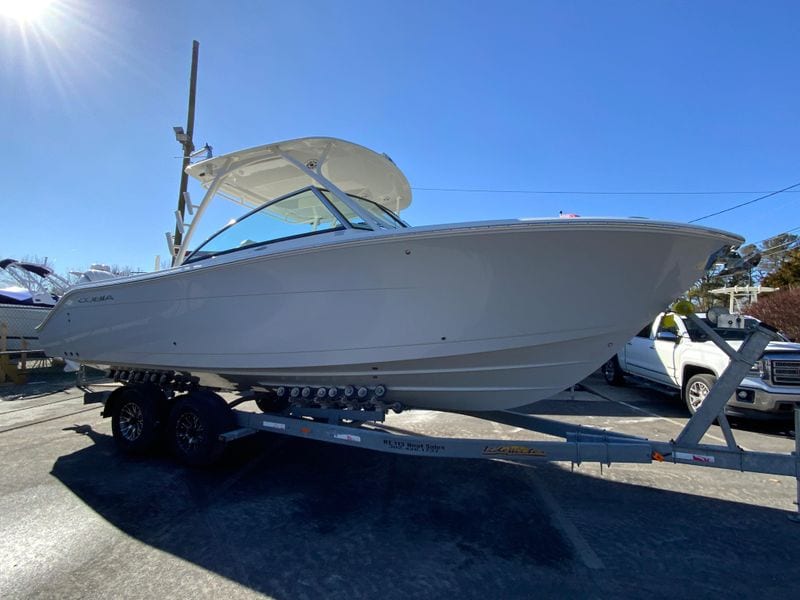 2025 Cobia 280 Dual Console boat on trailer under clear blue sky.