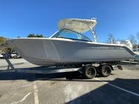 2025 Cobia 280 Dual Console boat on trailer, parked outdoors under clear blue sky.