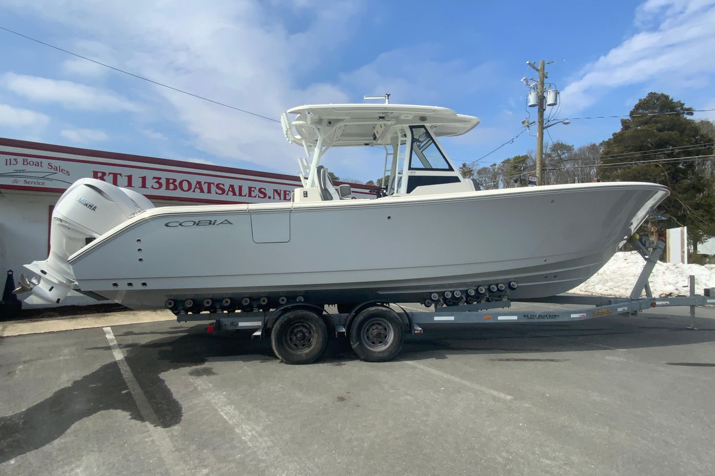 2026 Cobia 305 Center Console boat on trailer at dealership, clear sky background.
