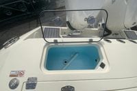 2026 Cobia 305 Center Console boat with open storage compartment and visible engine controls.