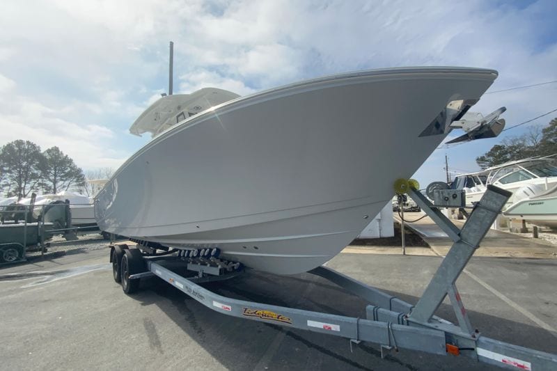 2026 Cobia 305 Center Console boat on trailer, parked outdoors under a cloudy sky.