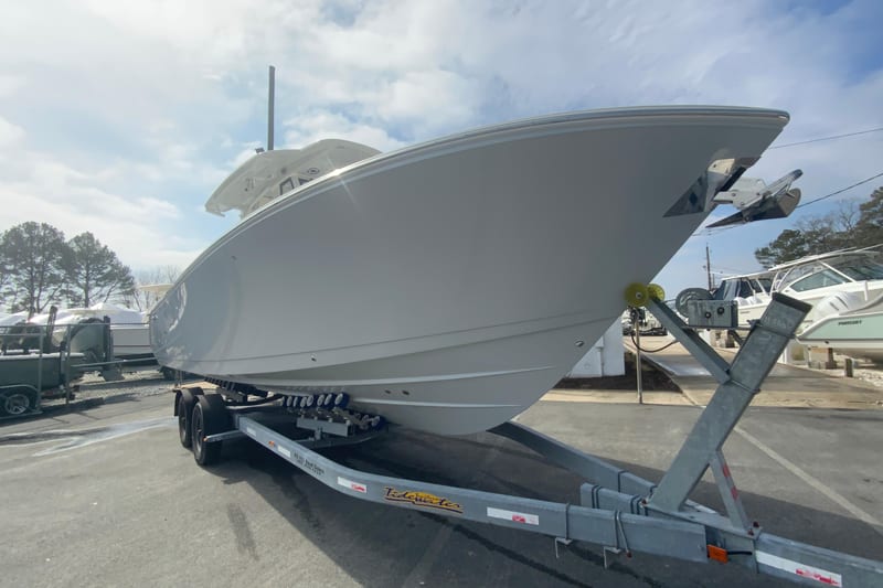 2026 Cobia 305 Center Console boat on trailer, parked outdoors under a cloudy sky.
