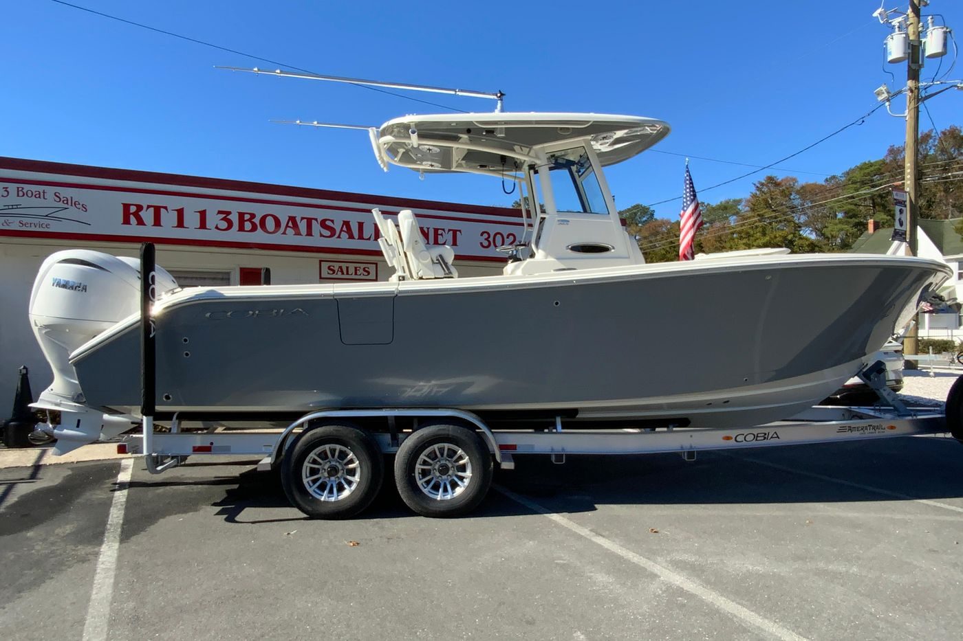 2026 Cobia 265 Center Console boat on trailer at dealership, sunny day.