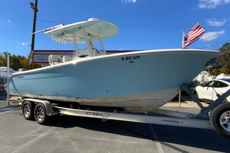 2019 Cobia 262 Center Console boat on trailer with American flag in background.