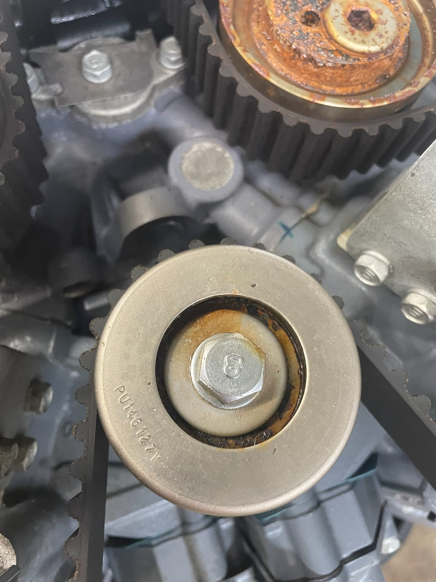 An idler pulley off a Yamaha powerhead with its old grease dried and darkened, held on the bench
