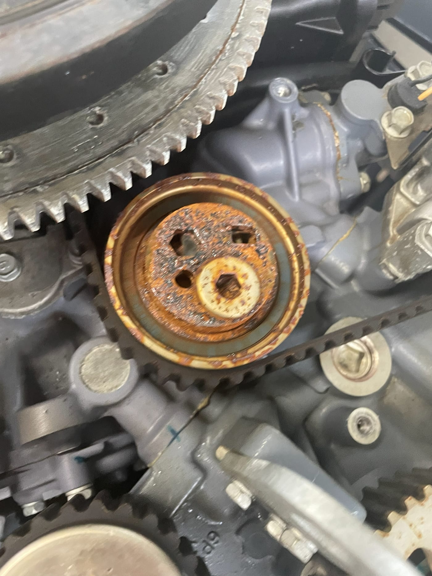 A rusted timing belt tensioner removed from a Yamaha outboard, corrosion across its face and pivot