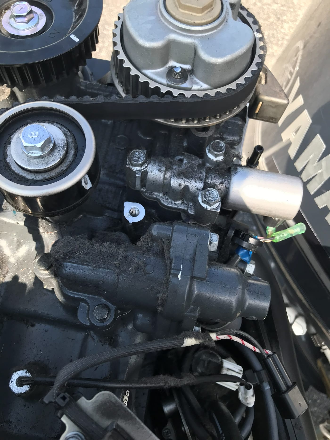Fine black rubber dust settled across the top of a Yamaha powerhead under the cowling, shed from the timing belt