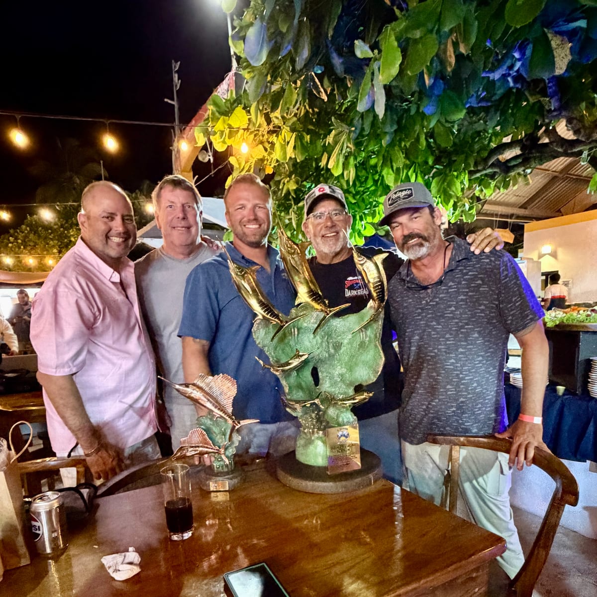 Zak Smith and four crewmates behind a large bronze marlin trophy at the El Salvador Billfish Tournament awards