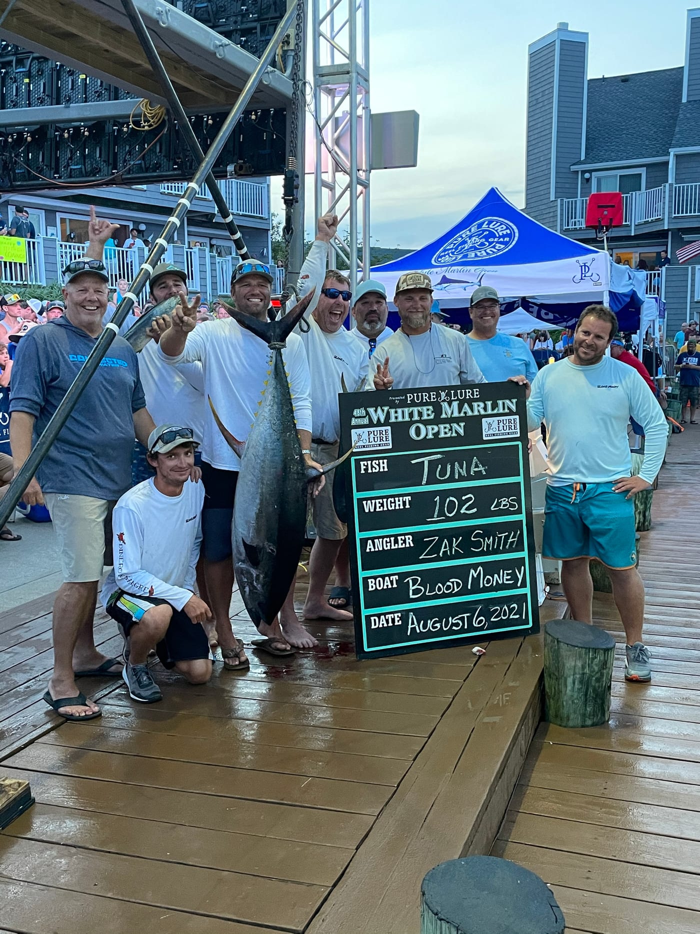 Zak Smith and the crew of Blood Money at the White Marlin Open scale beside a bluefin tuna, with the tournament board reading 102 pounds and his name as angler